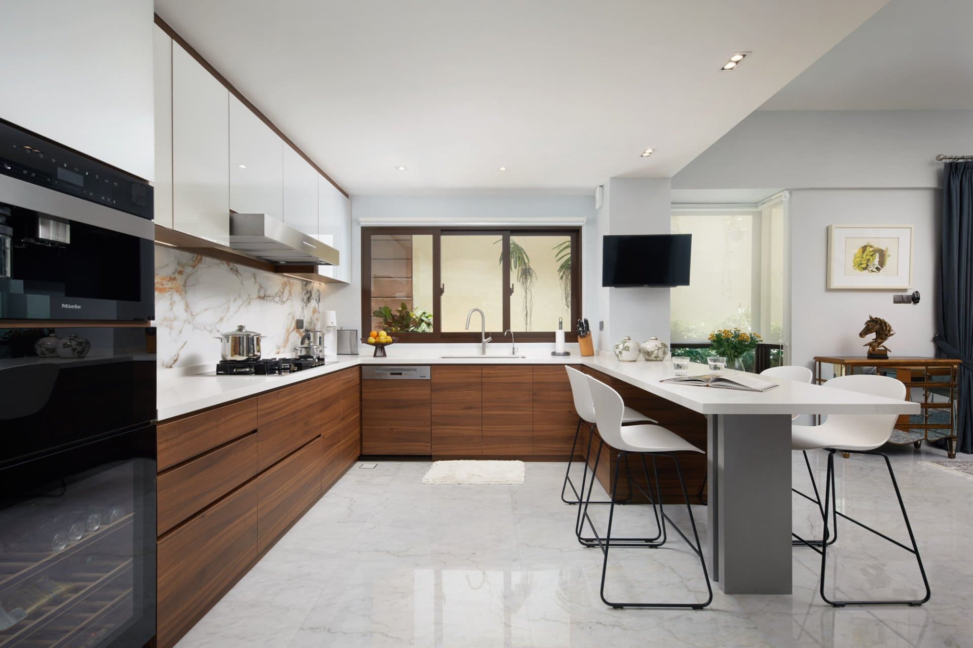 Contemporary kitchen with white and wood cabinets, marble backsplash, and a breakfast bar