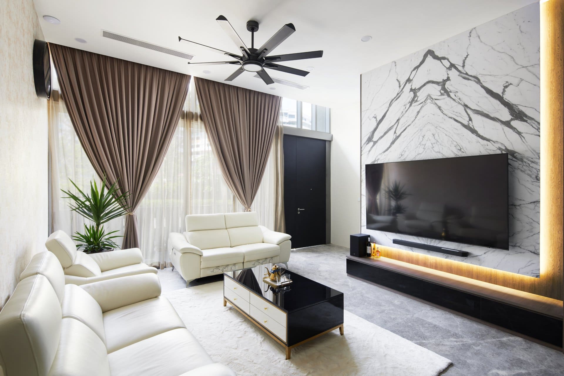 Modern living room with white sofas, marble TV wall, and brown curtains