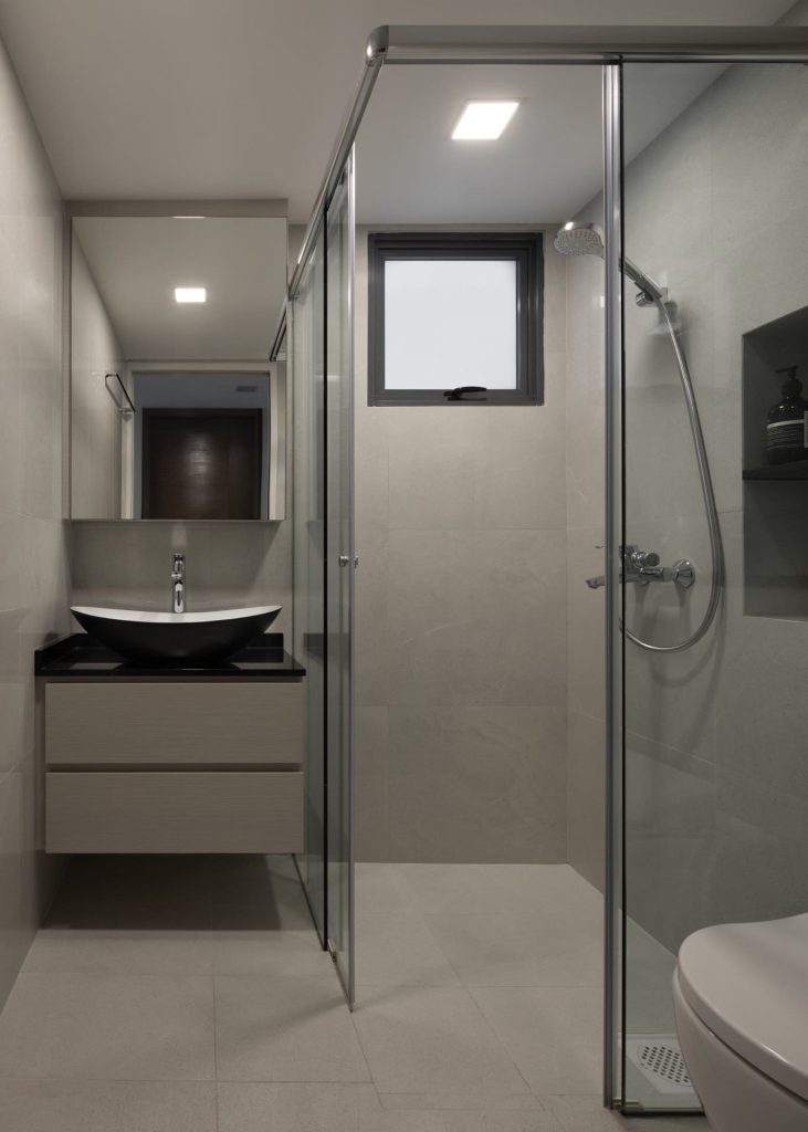 Modern bathroom with white floating vanity, black basin, round mirror, and glass shower