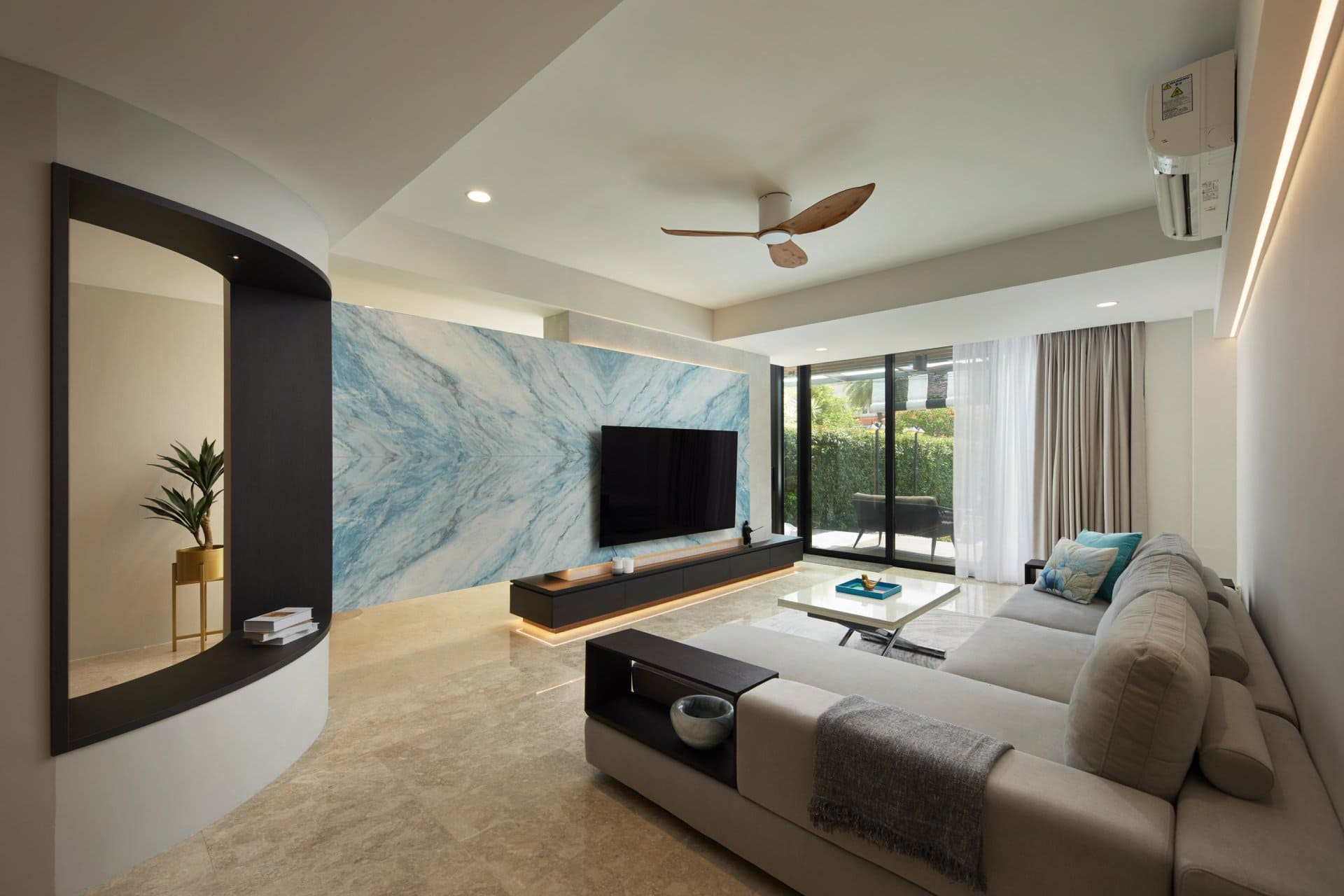 Modern living room with a large TV mounted on a blue marble accent wall and a light gray sofa