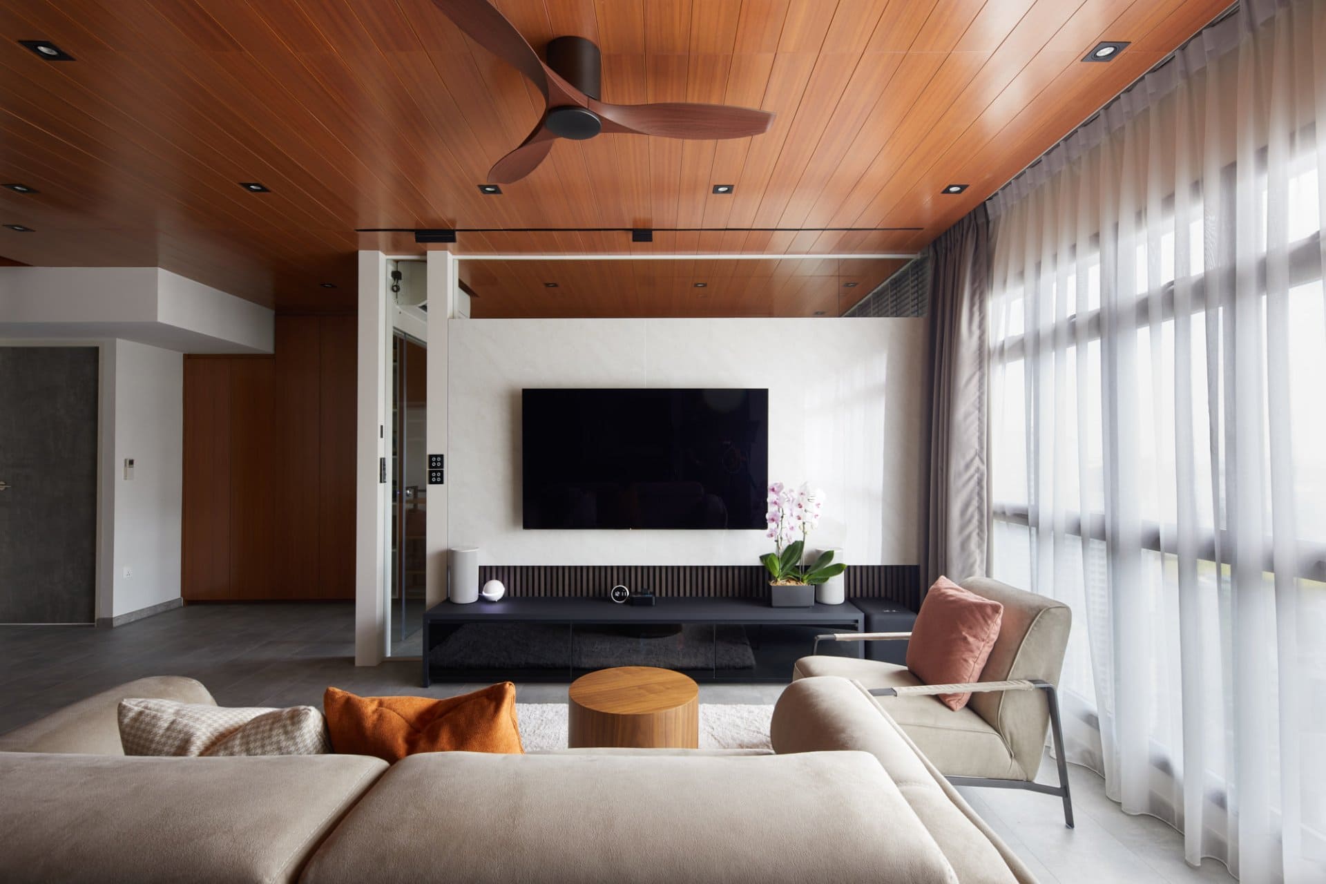 Modern living room with wood ceiling, TV, and light gray and orange accents