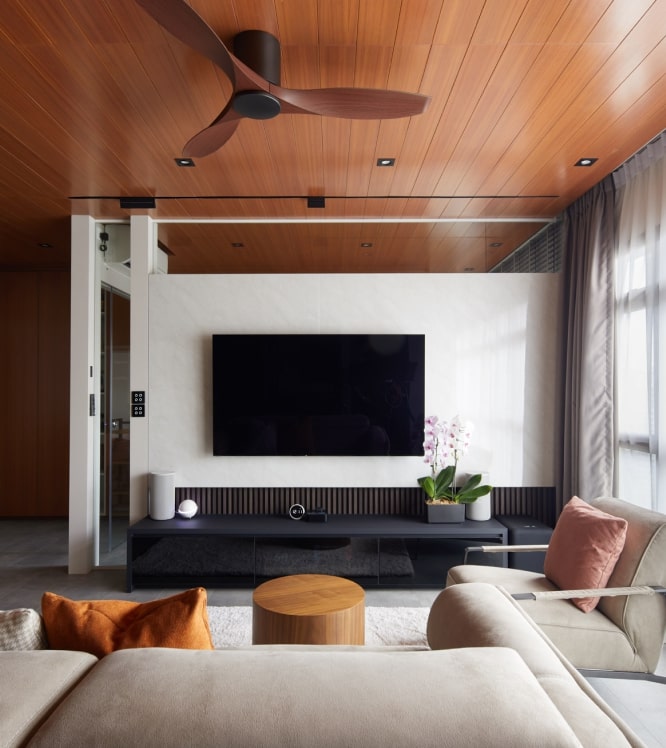 Modern living room with wood ceiling panel, sleek TV feature wall, and cosy neutral furniture setup.