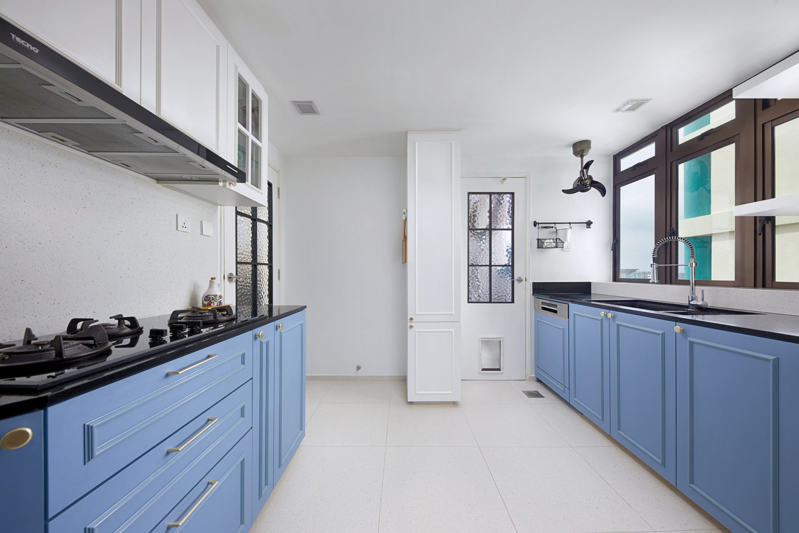Modern kitchen with blue shaker cabinets, black countertop and large windows.