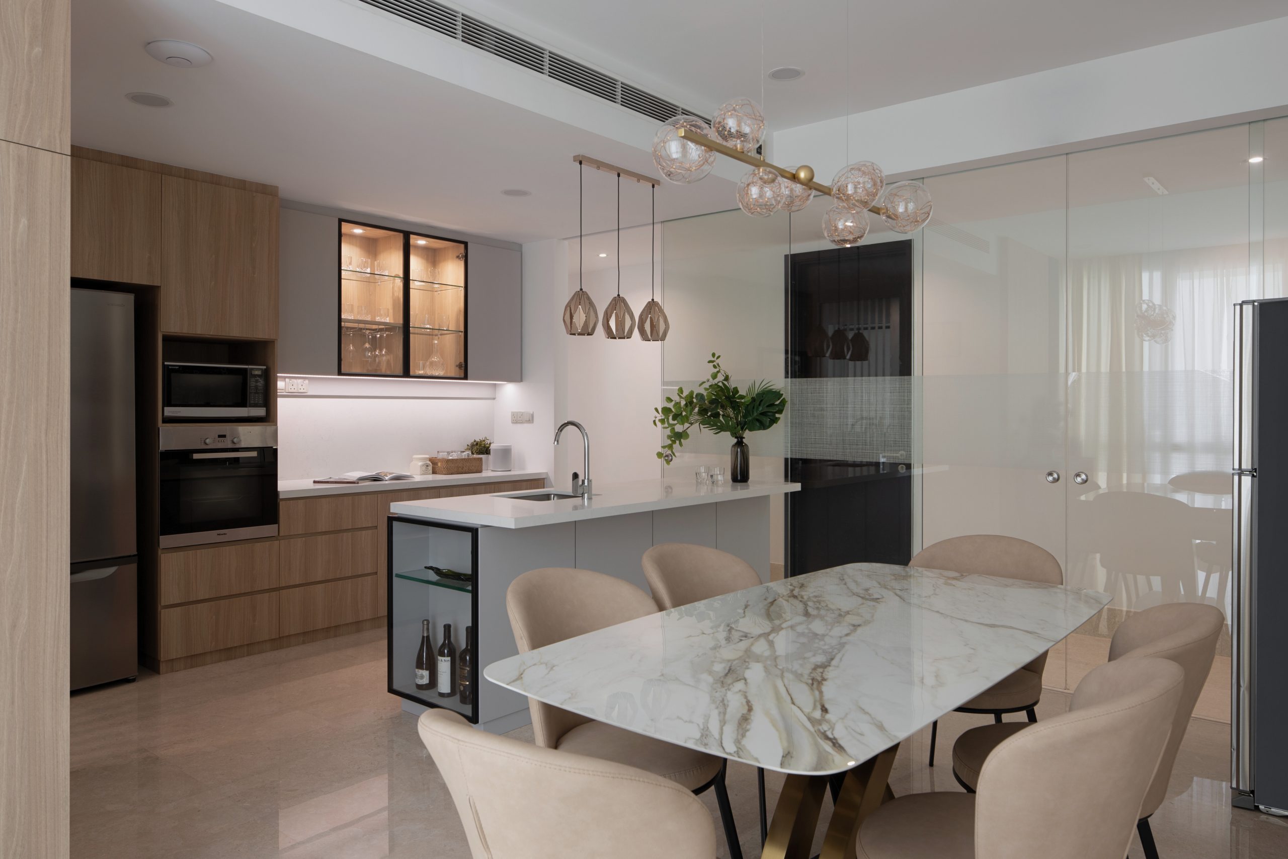 Luxury condo dining area with marble dining table, pendant lighting and a modern dry kitchen.