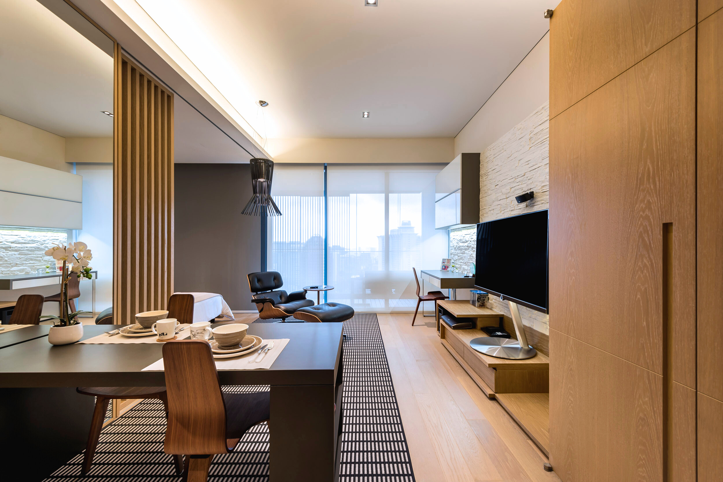 Modern luxe open-concept living and dining area with warm wood tones and soft natural lighting.