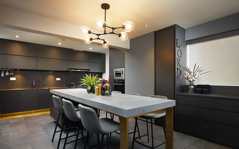 Luxurious dark kitchen interior with concrete island and modern chandelier.