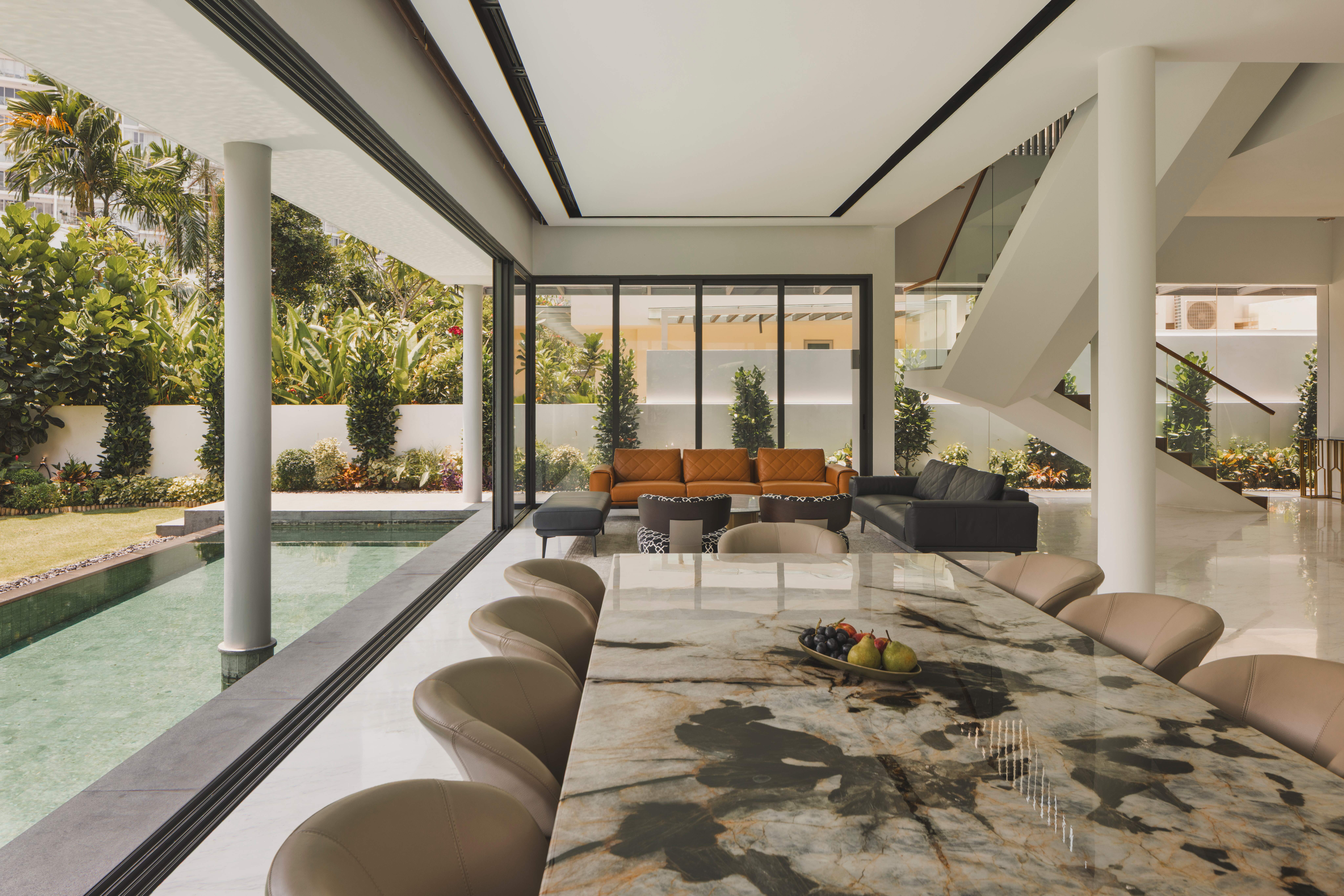 Indoor-outdoor dining and living space in a Singapore landed home with poolside view and marble dining table.