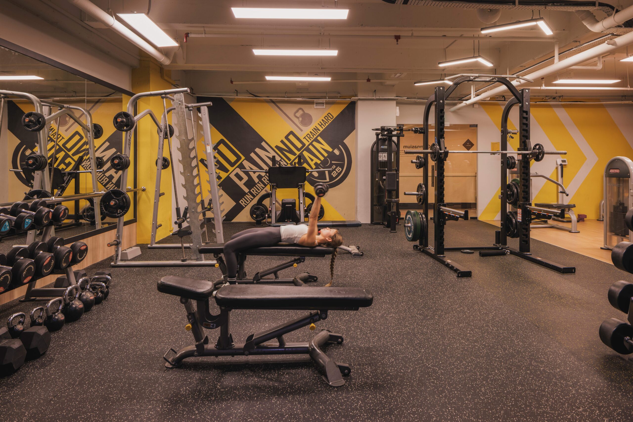 Condominium gym free weights zone with squat rack, rubber flooring and feature wall